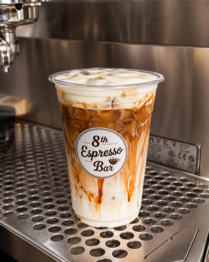 Iced caramel macchiato in an 8th Espresso Bar cup on the espresso machine drip tray