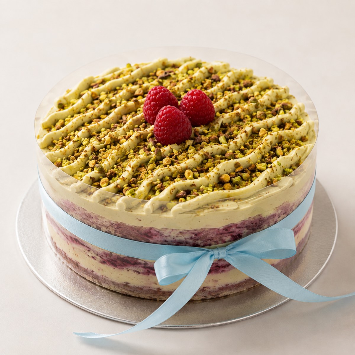Pistachio and Berry cake topped with crushed pistachios and fresh raspberries